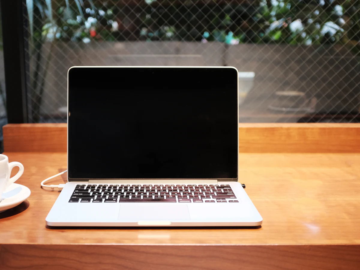 Laptop deschis pe o masă, lângă o cană de cafea, pregătit pentru lucrul la strategia SEO