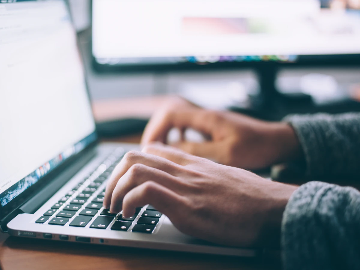 Persoană care scrie un articol SEO pe un MacBook Pro
