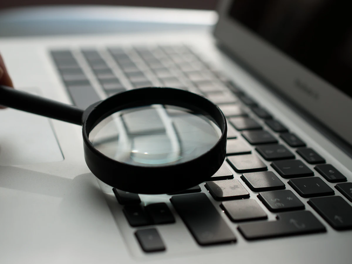 Lupă așezată lângă un laptop, simbol pentru verificarea SEO a unui site