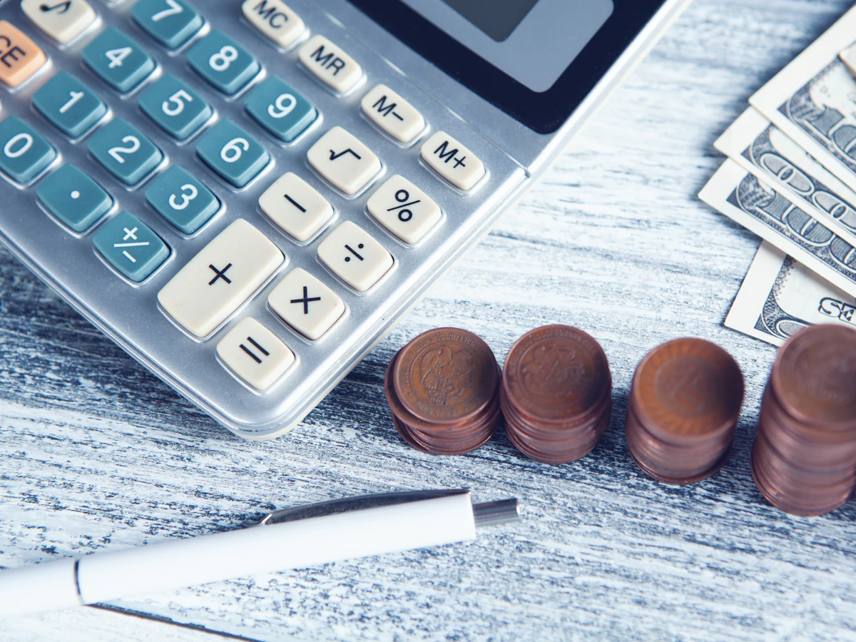 Calculator, pix și bancnote pe o masă, pentru calculul prețului serviciilor SEO