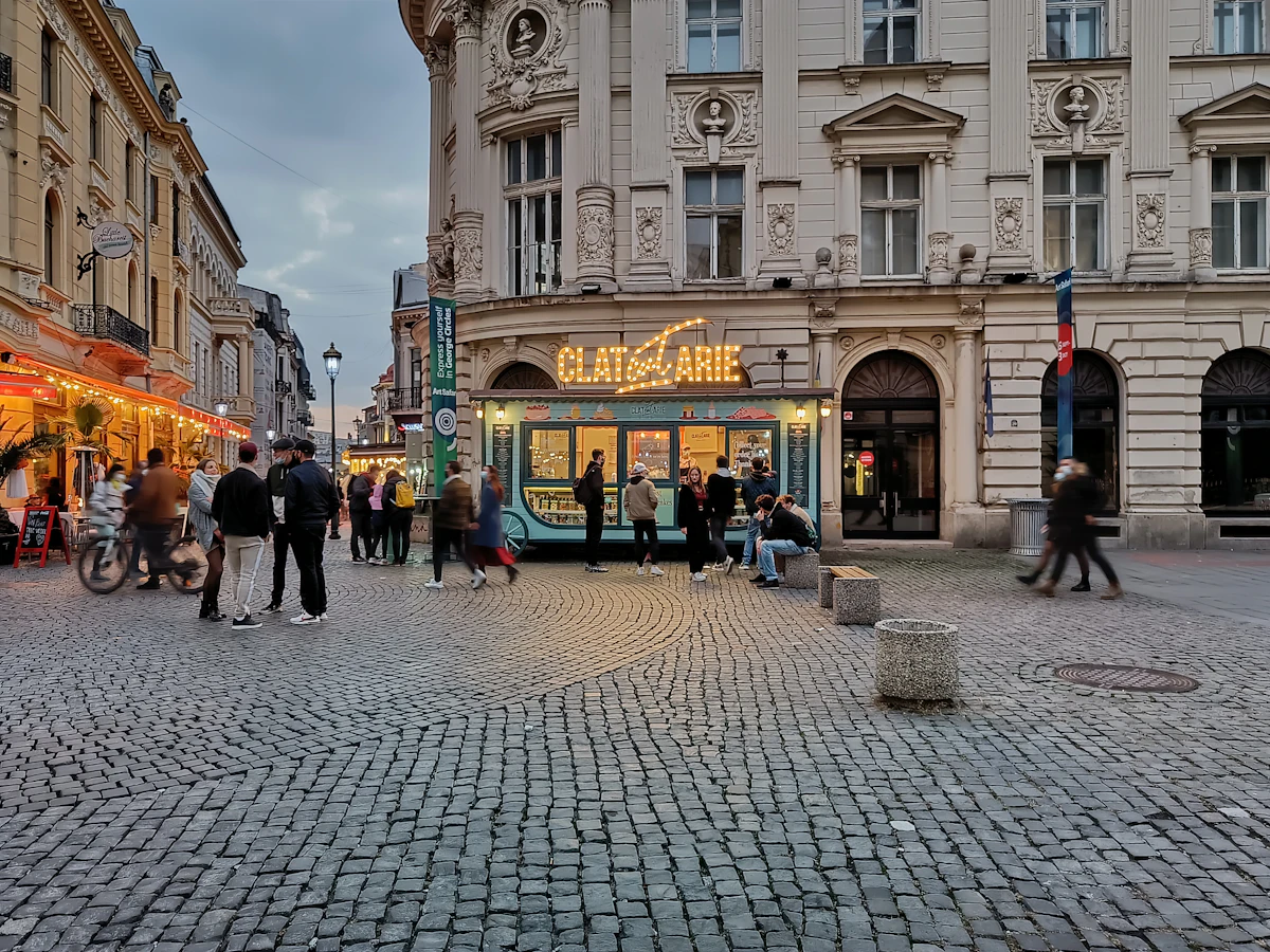 Oameni care se plimbă pe o stradă pietruită din centrul vechi al Bucureștiului