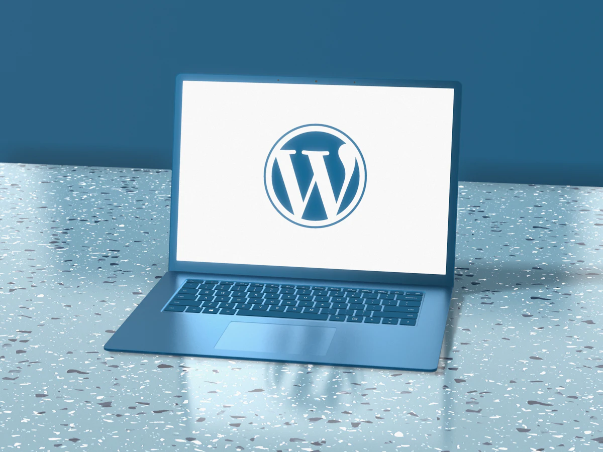 Laptop deschis pe un birou, cu logo-ul WordPress afișat pe ecran